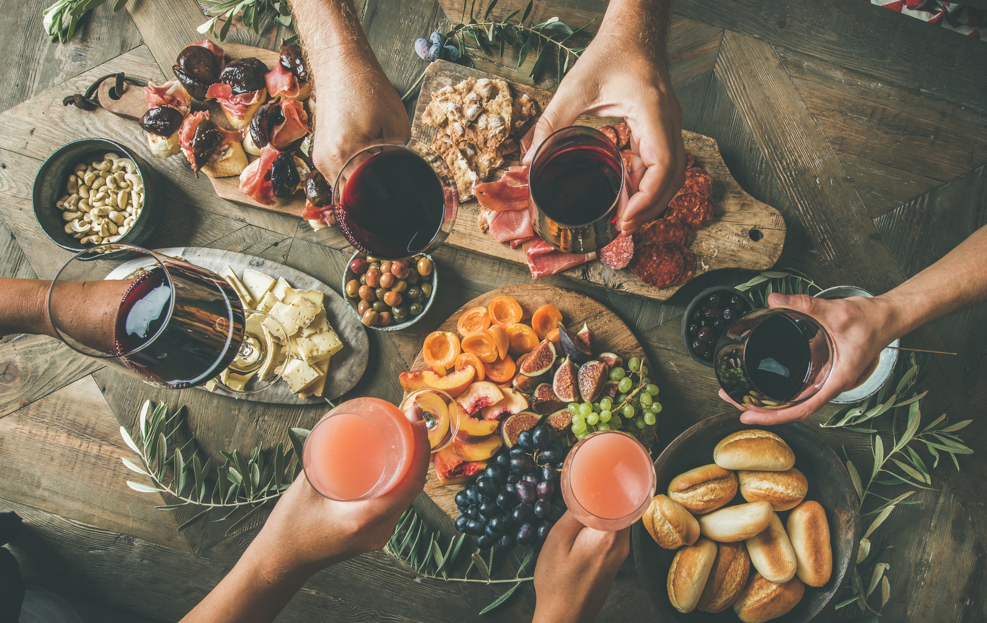 People having party sitting at table set with wine snacks